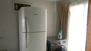 Une cuisine compacte avec un réfrigérateur blanc, un lave-linge et un petit plan de travail.