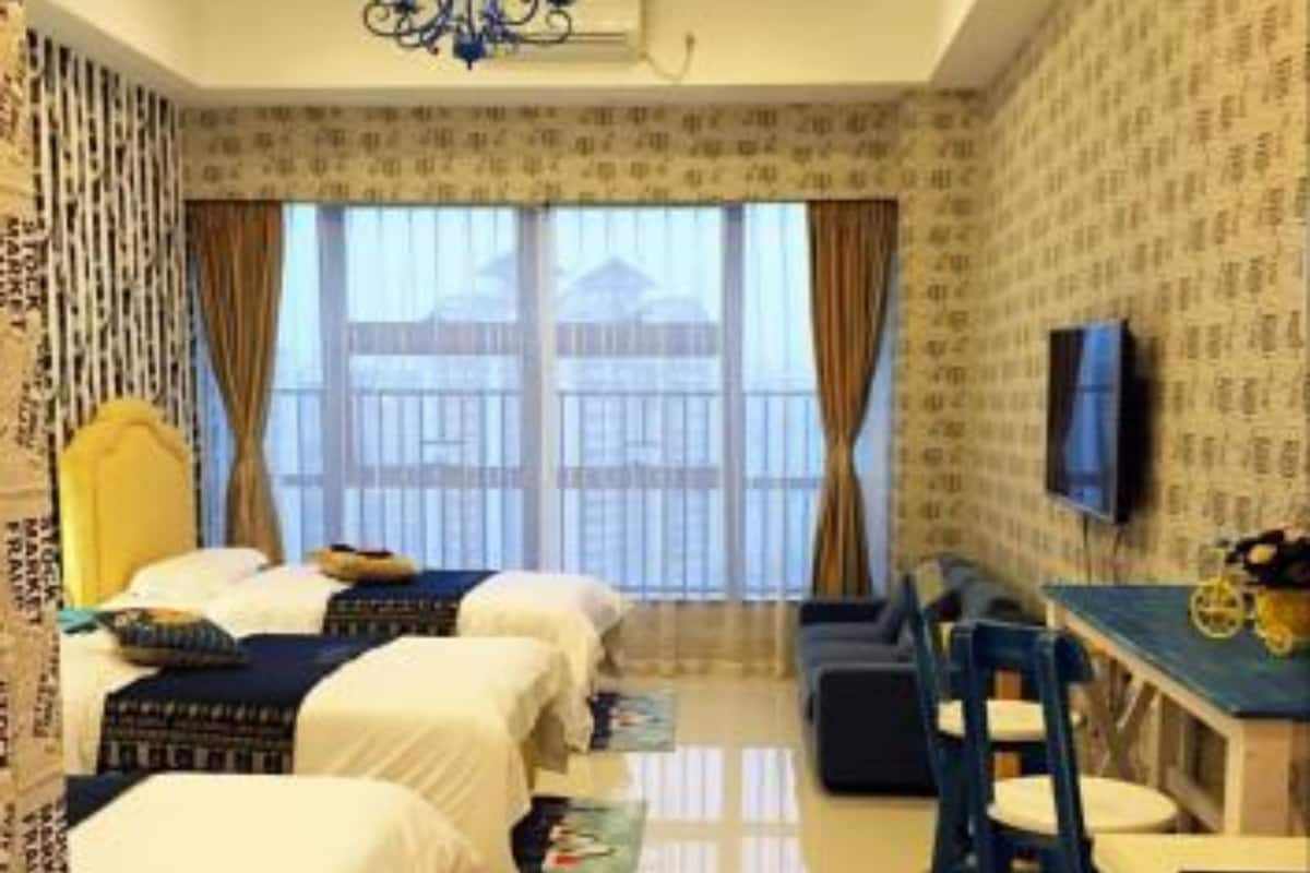 A hotel room with two beds, a desk, a chair, a TV, and a view of the outside.