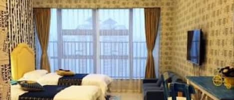 A hotel room with two beds, a desk, a chair, a TV, and a view of the outside.