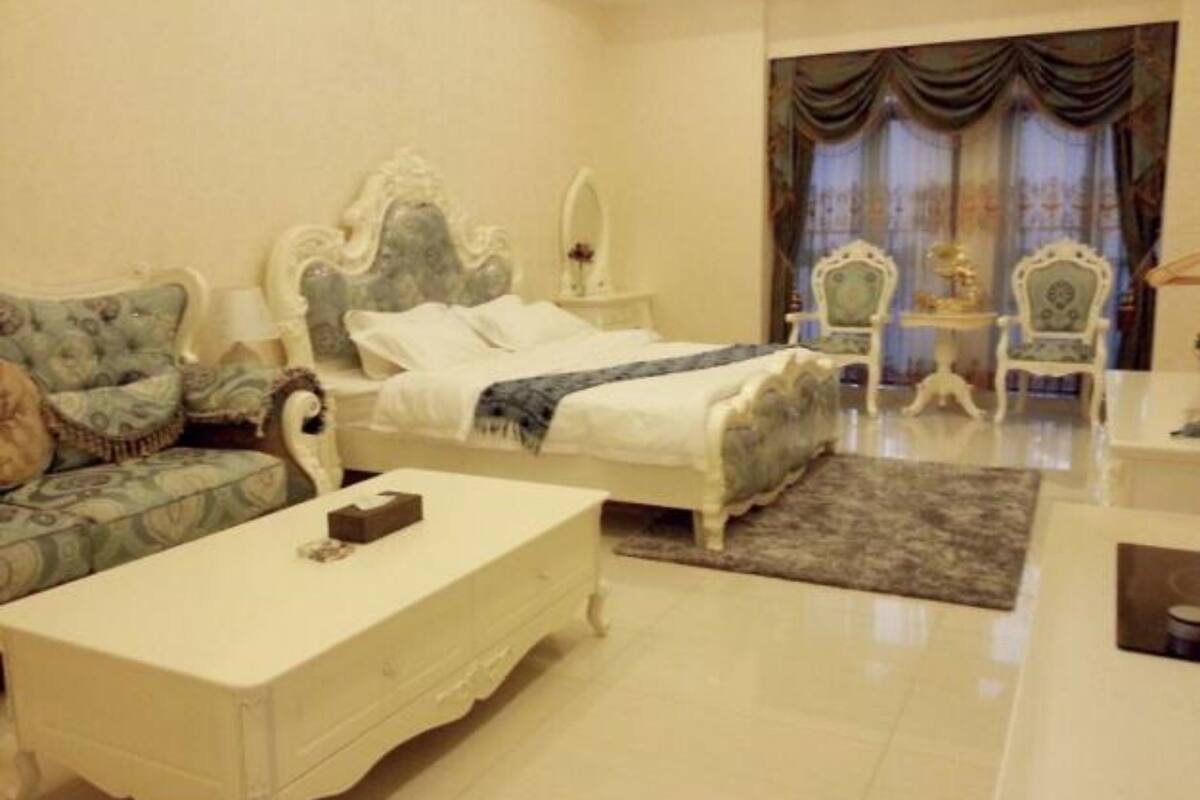 A bedroom with a bed, a sofa, a table, and a chair.