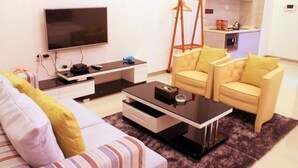 Una sala de estar moderna con un televisor de pantalla plana, una mesa de centro, un sofá y dos sillones.
