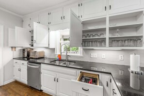 A modern kitchen with white cabinetry, a black countertop, and a built-in dishwasher. - Pool estate with soccer field, sleeps 16 (Lithonia)