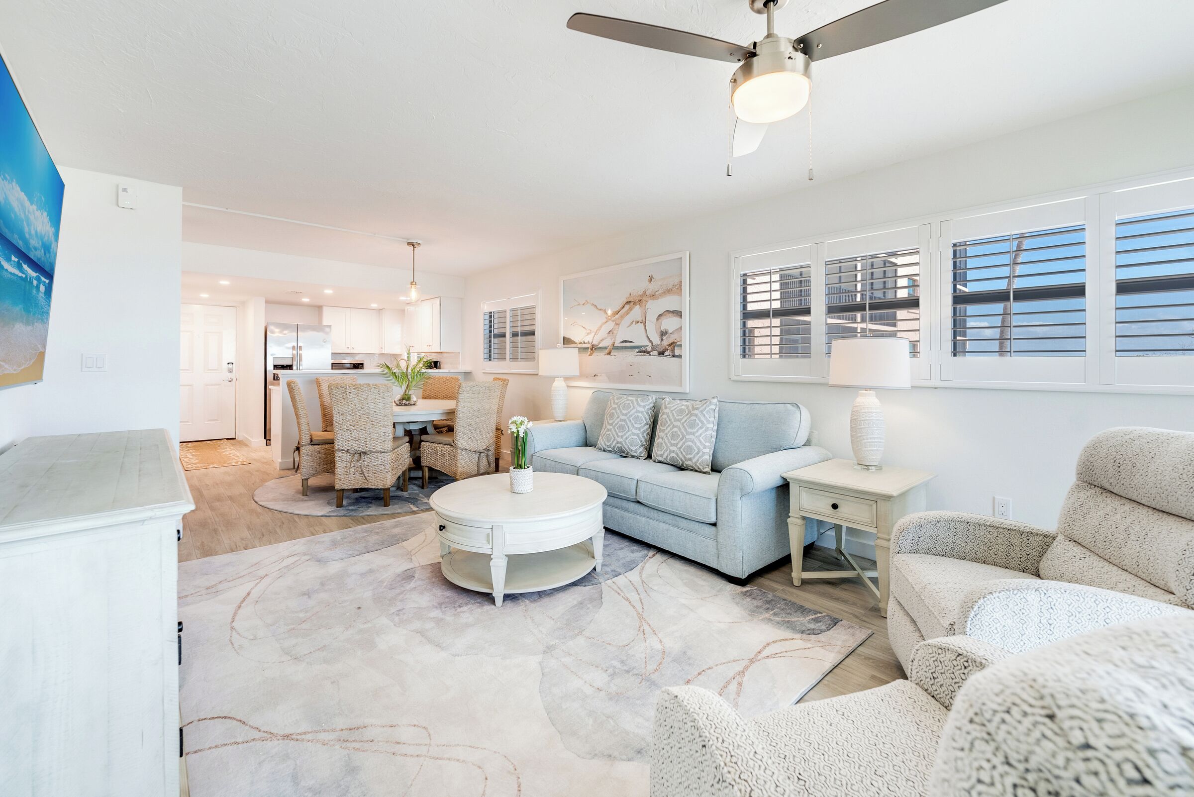 A modern living room with a light blue sofa, a white coffee table, and a ceiling fan.