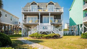 A two-story building with a porch, a sign reading "Tar Healhi", and a pathway leading to the entrance. - Tar Healin': Private Saltwater Pool and Ocean Views on Carolina Coast (Oak Island)