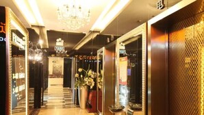 Un hall d’hôtel agrémenté d’un lustre, d’un comptoir d’accueil et d’un grand vase rempli de fleurs.