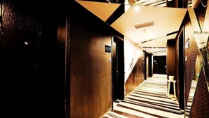 Un couloir d’hôtel avec un tapis à rayures, une pancarte indiquant le numéro de chambre 808 et un mur recouvert de miroirs.