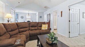 A living room with a sectional sofa, a coffee table, and a ceiling fan.