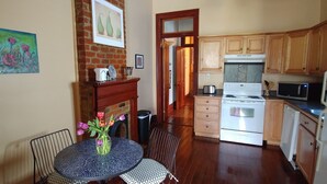 A kitchen with wooden cabinets, a stove, and a microwave. There is a dining table with chairs and a vase of flowers.