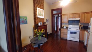 A kitchen with wooden cabinets, a stove, and a microwave. There is a dining table with a vase of flowers.