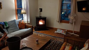 A cozy living room with a wood-burning stove, a sofa, a coffee table, and a television.