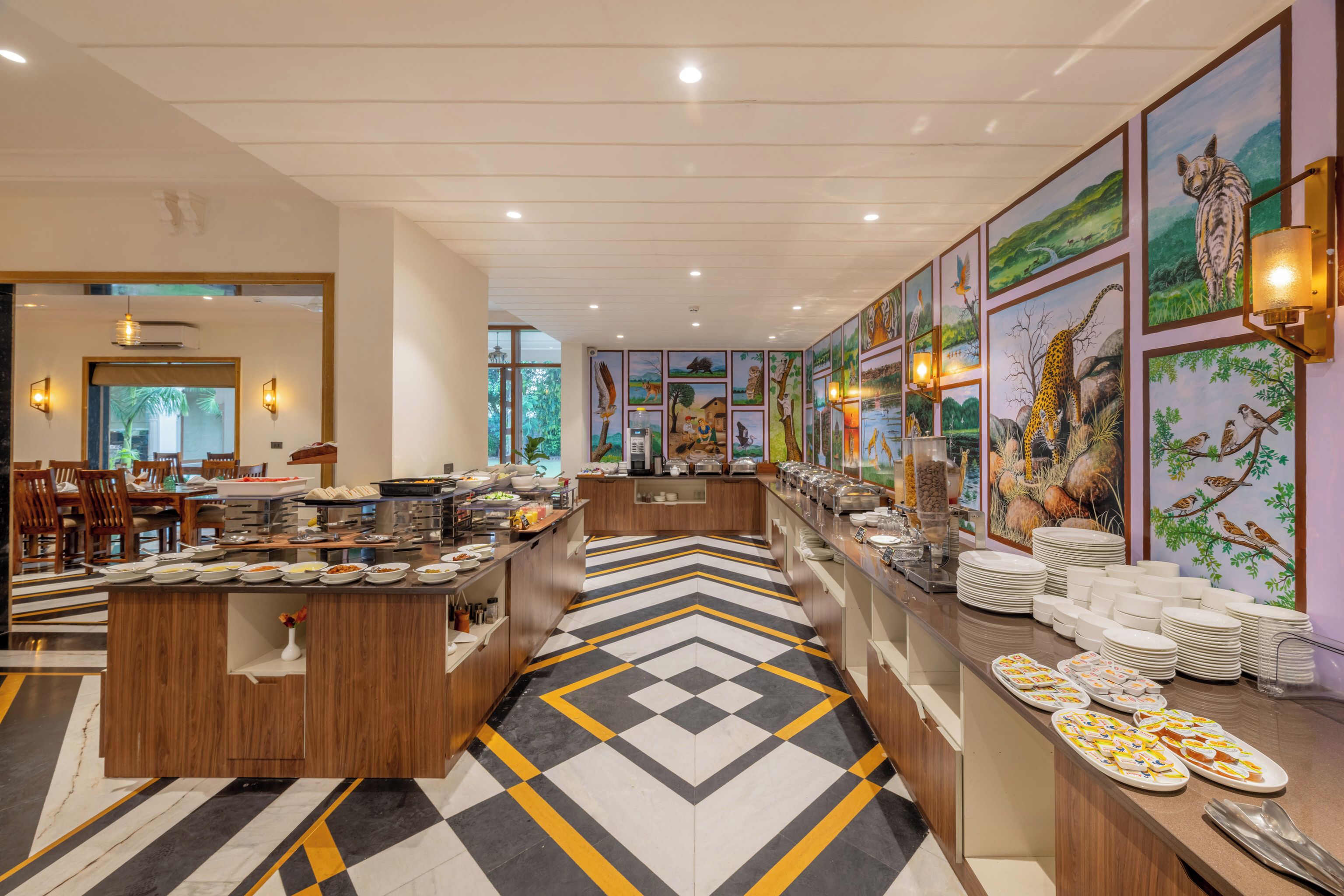 A hotel dining area with buffet counters, a check-in desk, and artwork on the walls.