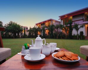 Enjoy tea service in a serene outdoor setting surrounded by lush greenery and palm trees.