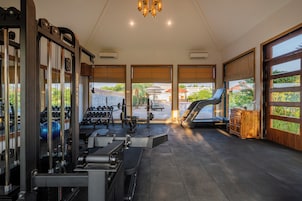Un gimnasio con equipo de ejercicio, una cinta de correr y vistas al exterior a través de amplios ventanales.