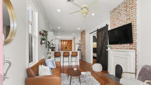 A modern living room with a fireplace, leather sofas, a coffee table, and a TV mounted on a brick wall.