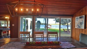 A wooden interior with a dining table, chairs, and a view of a lake.