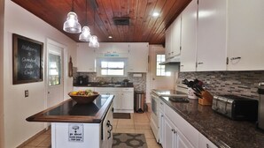 A modern kitchen with white cabinets, a central island, and a black countertop. There is a chalkboard sign on the wall and a sign on the island indicating a 'go ahead' message.