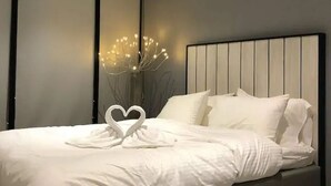 A modern bedroom with a large bed, a dark wall, and a decorative light fixture. - Stazion Services Alila (Kuala Lumpur)