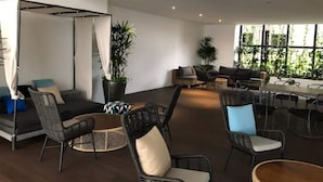 A spacious indoor area with wicker furniture, a swing, and potted plants. - Stazion Services Alila (Kuala Lumpur)