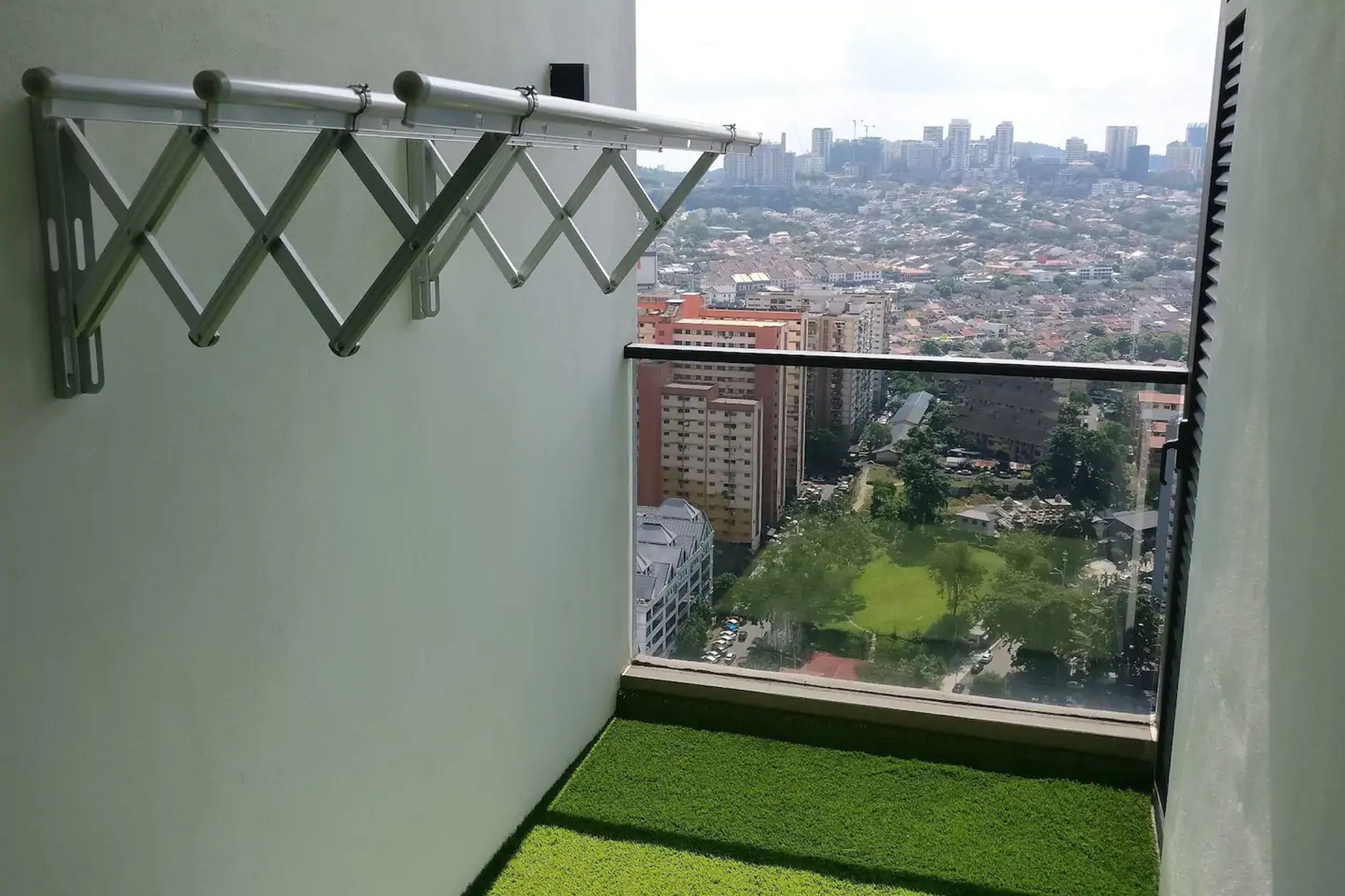 Un balcón con barandilla de metal y vista a la ciudad.