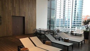 A modern lounge area with wooden flooring, sun loungers, a table, and chairs. - Stazion Services Alila (Kuala Lumpur)