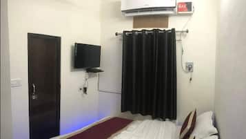 Habitación de hotel con cama, televisor de pantalla plana en la pared, aire acondicionado y una puerta.