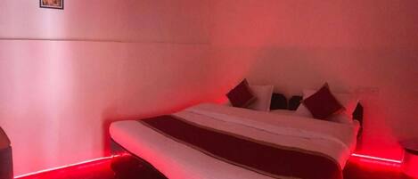 A bedroom with a bed, pillows, and a nightstand. There are three framed pictures on the wall.