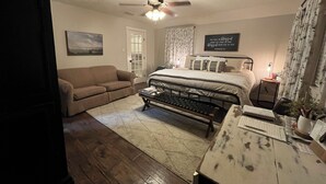 A bedroom with a bed, a desk, a chair, a sofa, a ceiling fan, and a door. - Best Getaway in East TX! ElKen Retreat:Spa,Pool,Hot tub,Massage,Breakfast,Relax (CANTON)