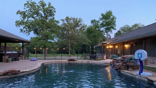A swimming pool with a basketball hoop, surrounded by trees and a wooden building. - Best Getaway in East TX! ElKen Retreat:Spa,Pool,Hot tub,Massage,Breakfast,Relax (CANTON)
