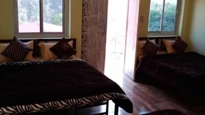 A room with two beds, a window, and a door leading outside. - Panchvati cottage (Narendranagar)
