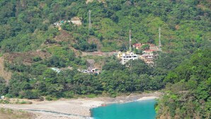 A coastal area with a beach, a river, and a hillside with buildings. - Panchvati cottage (Narendranagar)