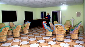 A room with wicker chairs and tables, a counter, and a tiled floor. - Panchvati cottage (Narendranagar)