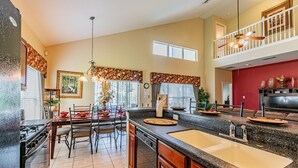 A spacious kitchen with a large island, a dining area with chairs, a ceiling fan, and a view of the living area. - 7 Beds, 7 Bath Acadia Estates Home with Private Pool and Spa Minutes to Disney! (Kissimmee)