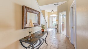 A hallway with a console table, a mirror, and a potted plant. - 7 Beds, 7 Bath Acadia Estates Home with Private Pool and Spa Minutes to Disney! (Kissimmee)
