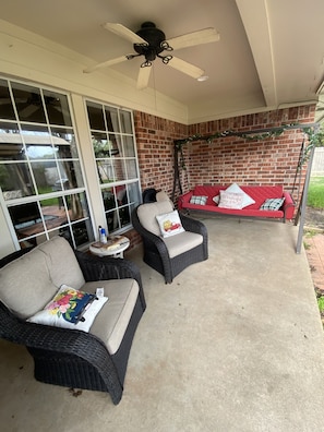 A covered patio area with wicker furniture, a red sofa, and a ceiling fan. - Football Games, A&M Events, Parents Night, etc..our home wins! (College Station)