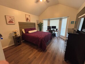 A bedroom with a wooden headboard, a bed with a maroon bedspread, a desk with a computer, and a large window with blinds. - Football Games, A&M Events, Parents Night, etc..our home wins! (College Station)