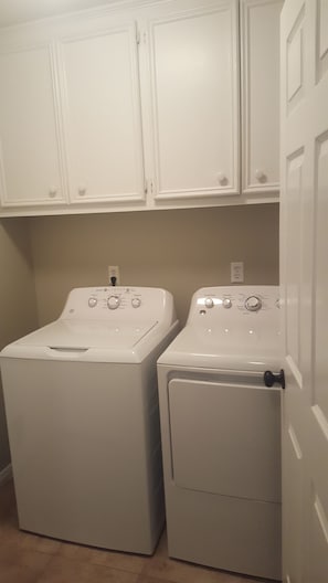 A laundry room with two front-loading washing machines and white cabinets above. - Football Games, A&M Events, Parents Night, etc..our home wins! (College Station)