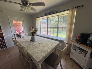 A dining area with a table set for two, a ceiling fan, a window with a view of the outdoors, and a coffee station. - Football Games, A&M Events, Parents Night, etc..our home wins! (College Station)