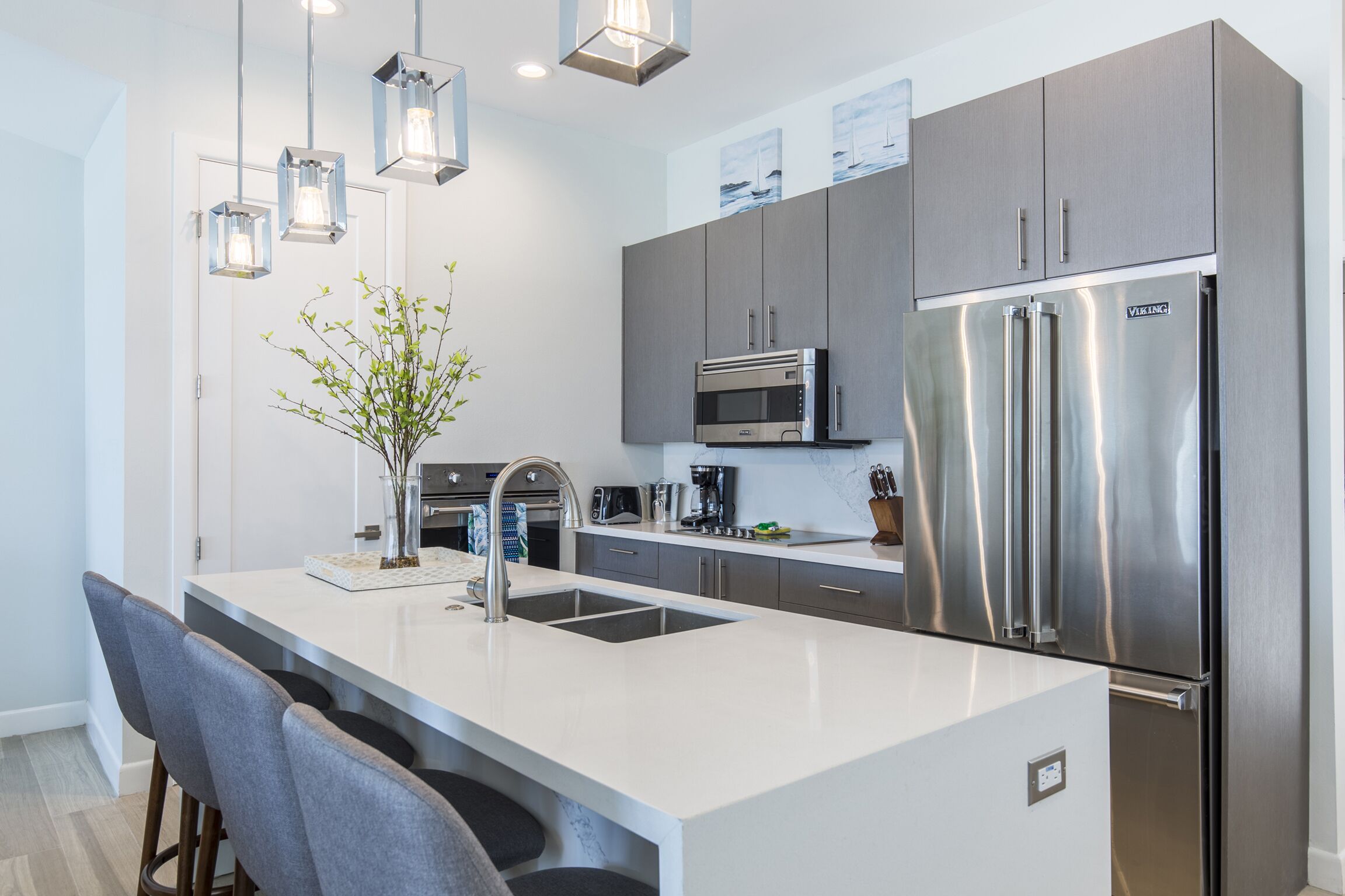 A modern kitchen with a central island, stainless steel appliances, and pendant lighting.