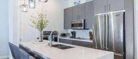 A modern kitchen with a central island, stainless steel appliances, and pendant lighting.