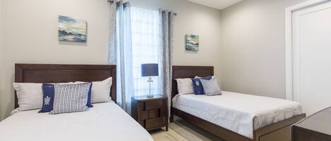A hotel room with two beds, a ceiling fan, and artwork on the walls.