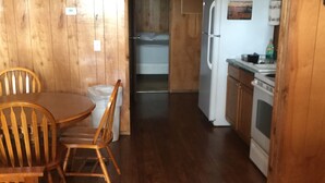A wooden interior with a dining area, a kitchen, and a small closet.