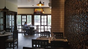 A restaurant with a brick wall, hanging pendant lights, and a large window. - Hotel Bikram (Tezpur)