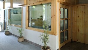 A room with wooden paneling, large windows, and potted plants. - Hotel Bikram (Tezpur)