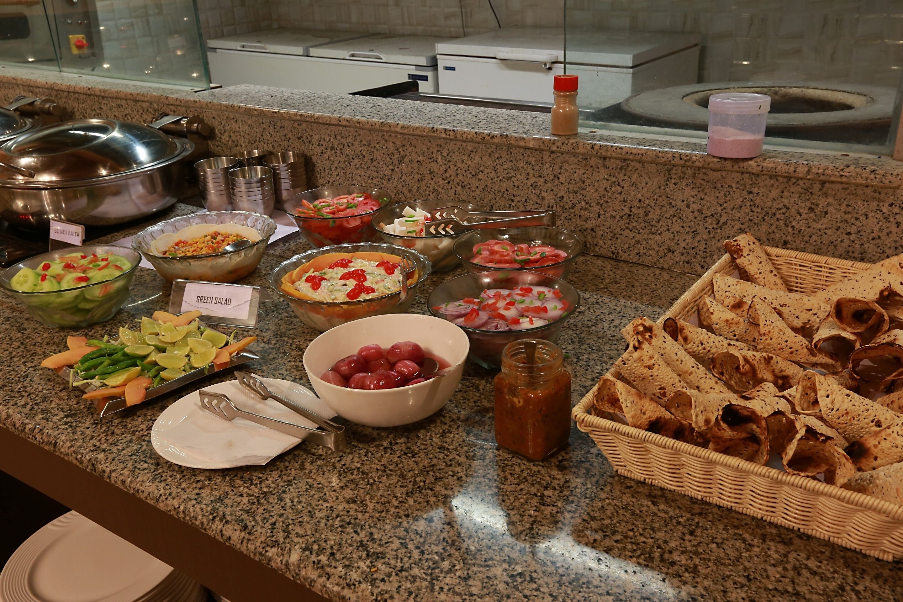Ein Buffet mit verschiedenen Speisen, darunter Salate, Obst und Brot.