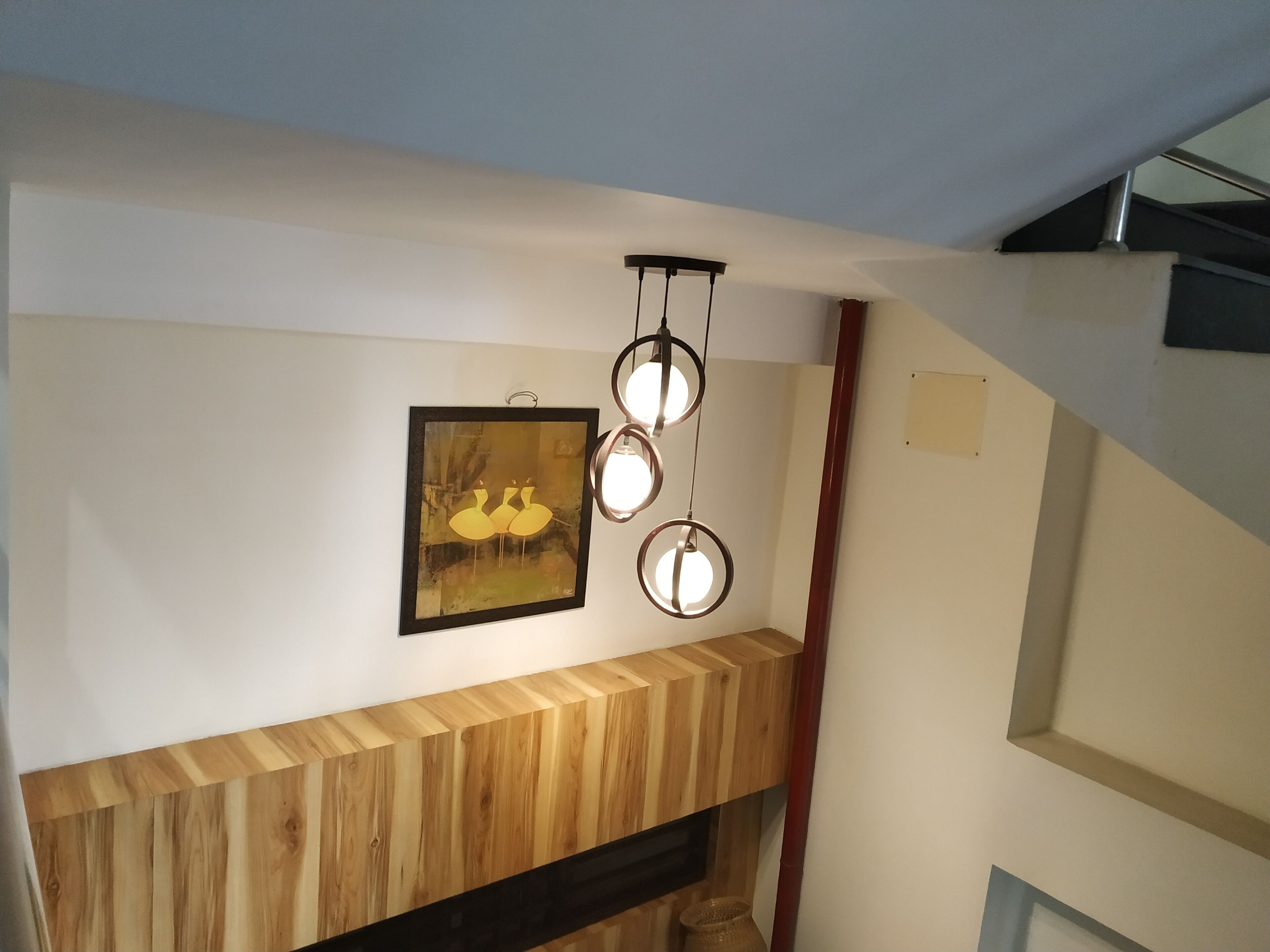 Et moderne interiør med en træpanelfod, en indrammet kunstgenstand og en unik, rund lampe.