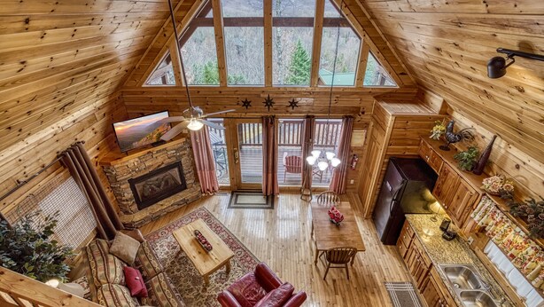 Un vaste chalet de style loft doté d’un haut plafond, d’un intérieur en bois, d’une cheminée, d’un coin repas et d’une cuisine équipée d’un évier et d’une cuisinière.