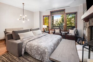 Ein modernes Schlafzimmer mit einem großen Bett, einer Sitzecke mit Kamin und großen Fenstern mit Blick ins Freie.