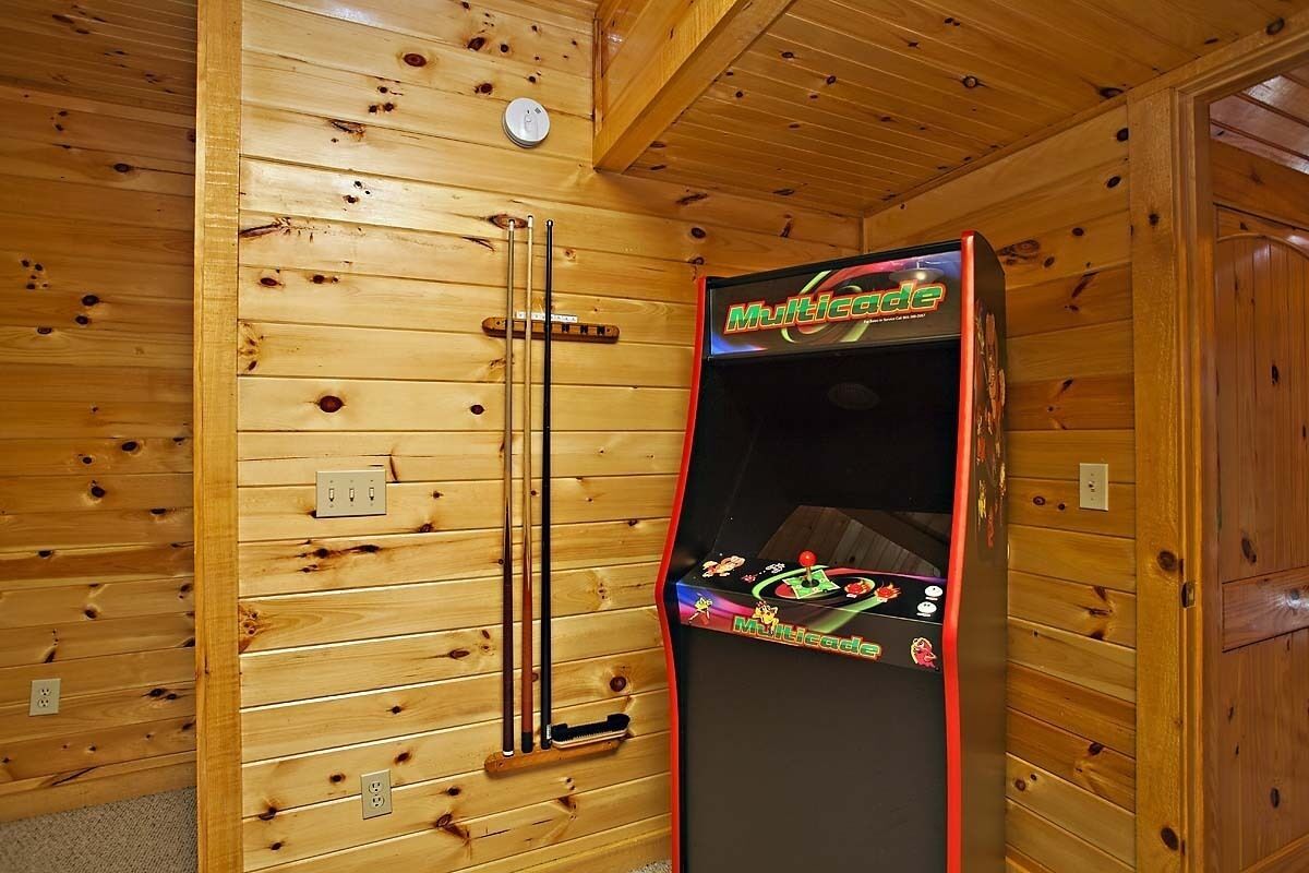 Une pièce aux murs lambrés, où se trouve une borne d’arcade Multicade.