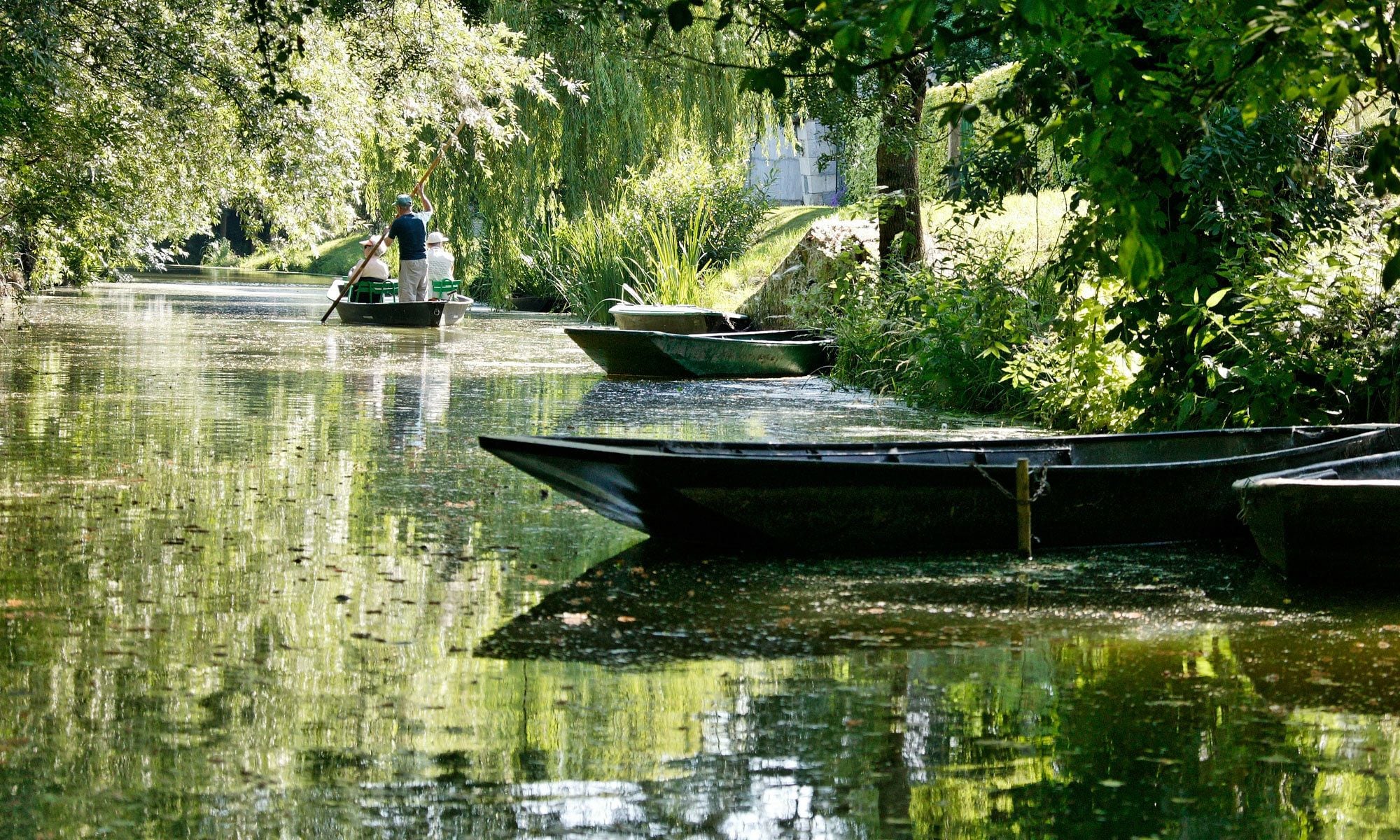 A calm river with boats and greenery.