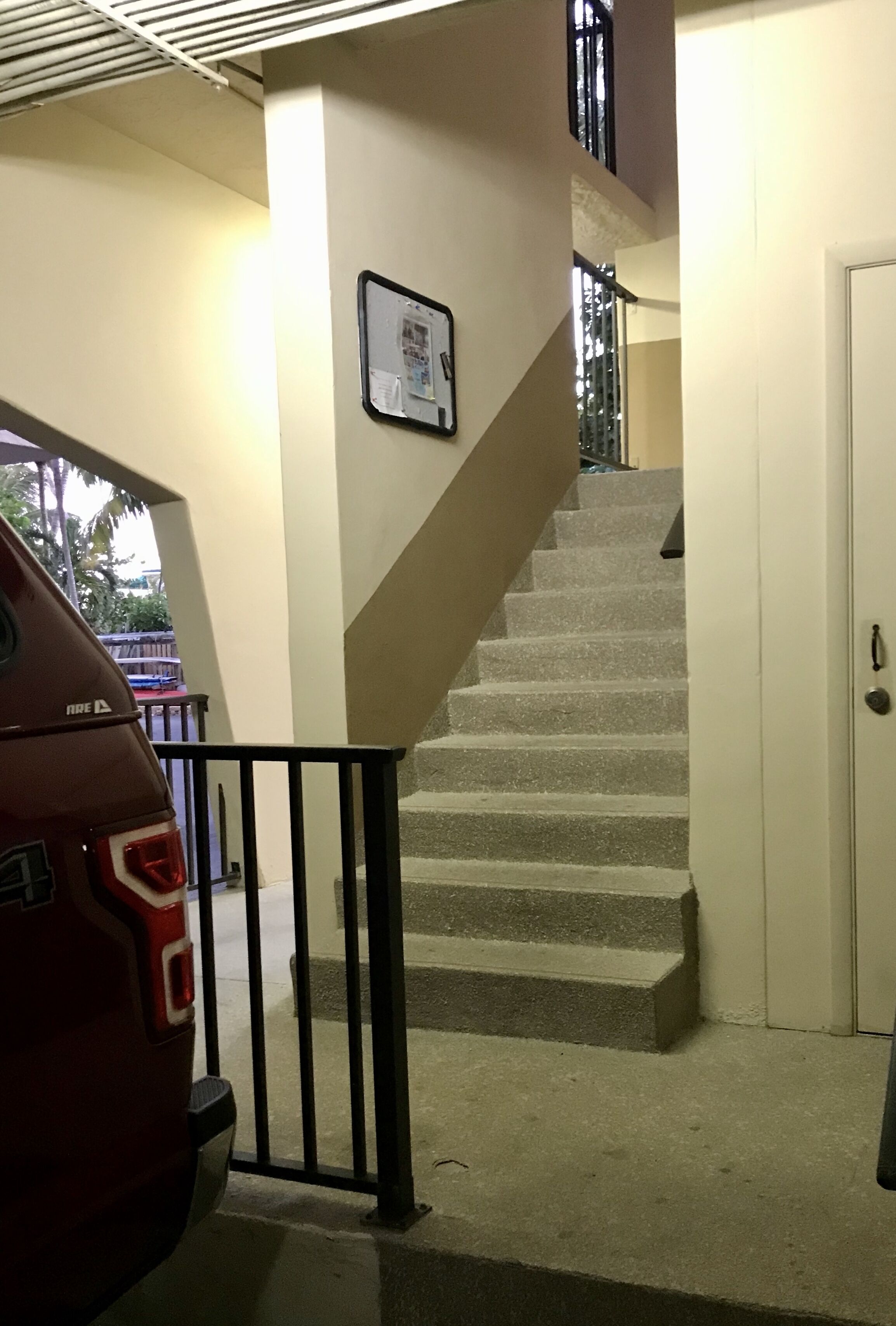 A staircase with a metal railing, a door, and a wall-mounted bulletin board.